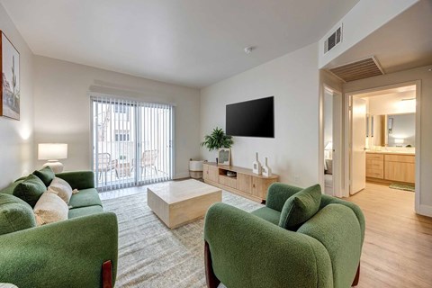 A living room with green chairs and a flat screen TV.