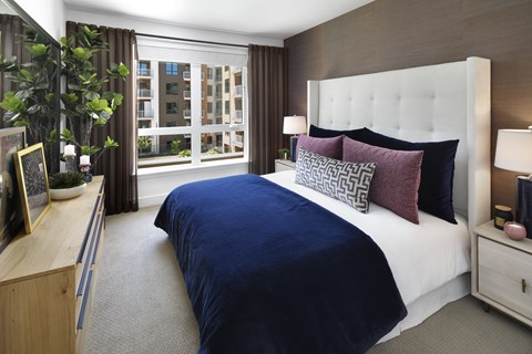 A bedroom with a large bed and a window with a view of a building.