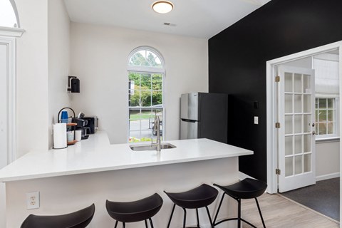 a kitchen with a white counter top, a sink, and a refrigerator