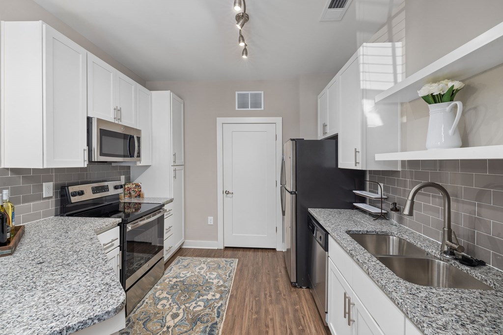 A kitchen with black appliances and white cabinets.