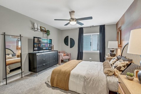 A bedroom with a bed, dresser, and a ceiling fan.