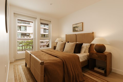 A bedroom with a large bed and a view of a balcony.