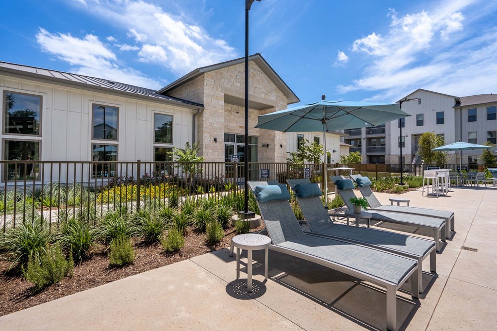 a patio with chairs and umbrellas in front of a building
