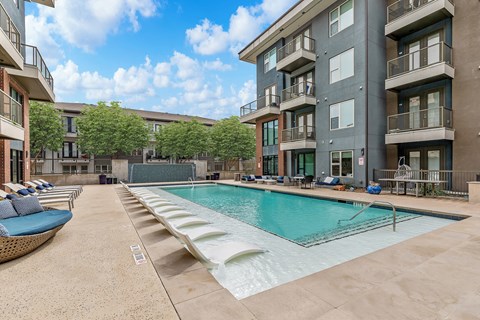 A large swimming pool is surrounded by apartment buildings.