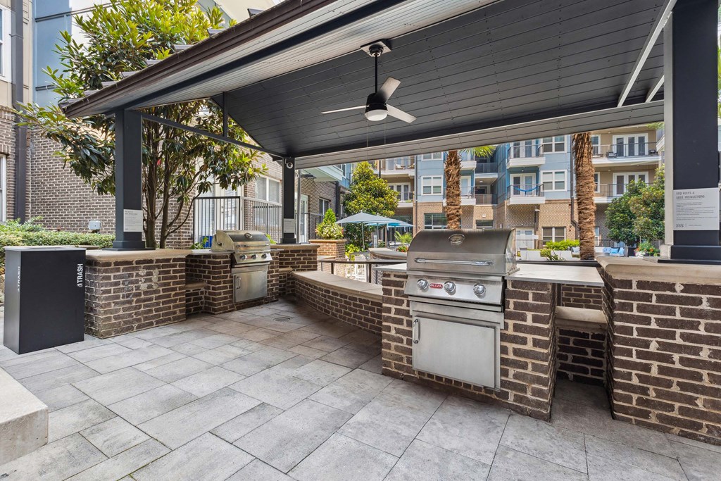 an outdoor kitchen with a grill and a ceiling fan