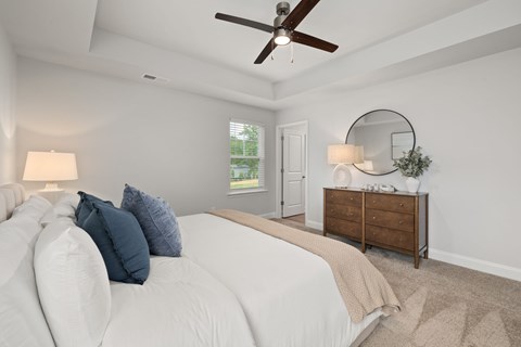 A bedroom with a white bed and a wooden dresser.