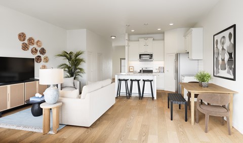 A modern living room with a white sofa, a wooden dining table, and a television.