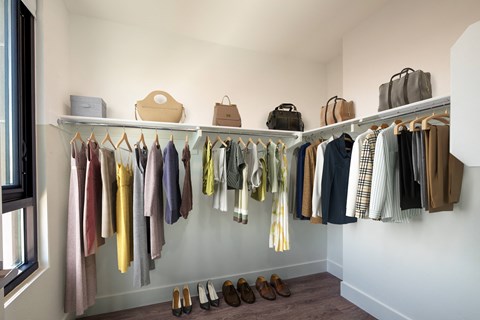 a walk in closet with white walls and a white rod with clothes hanging on it and shoes