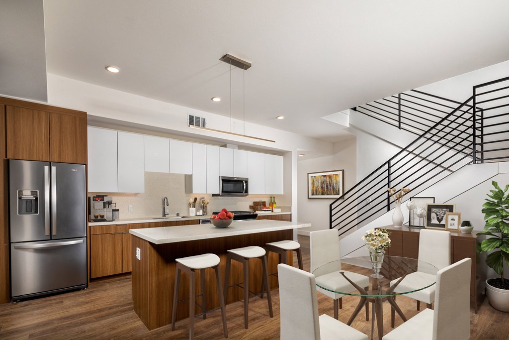a kitchen and dining area with a staircase in the background