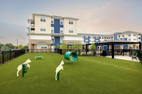 A playground with a slide and two animal figures on the grass in front of a building.