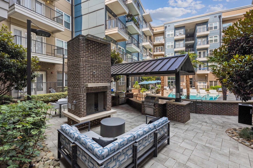 a patio with a fireplace and a pool in front of an apartment building