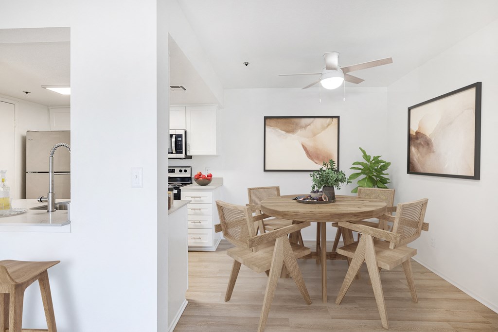 a dining area with a wooden table and chairs and a kitchen in the background