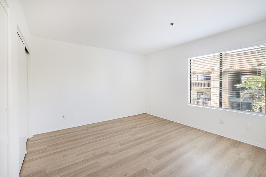 a bedroom with hardwood floors and a large window