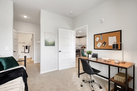 an office with a desk and a bed in a room with a door to a