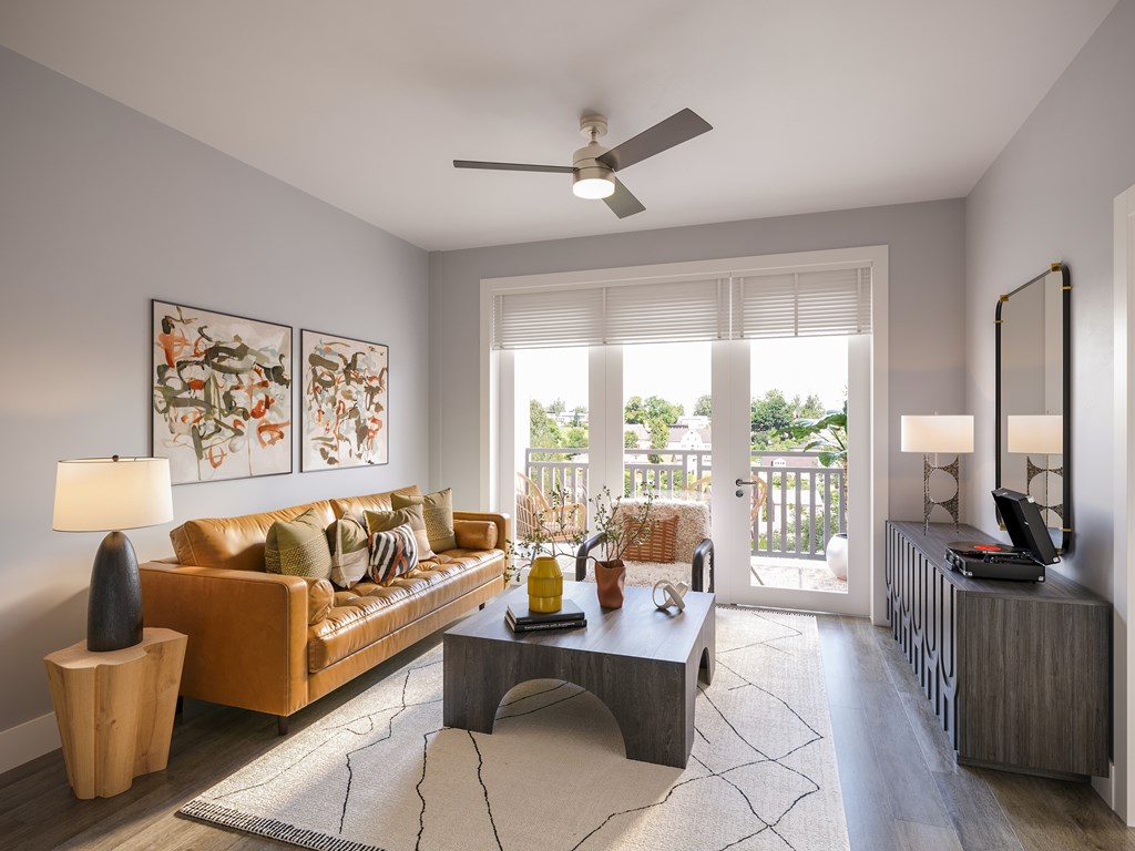 A living room with a yellow couch, a coffee table, and a ceiling fan.