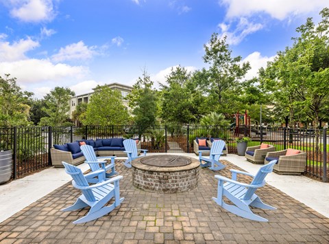 A fire pit surrounded by blue chairs in a backyard setting.