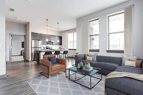 a living room and kitchen area with grey couches and a glass coffee table