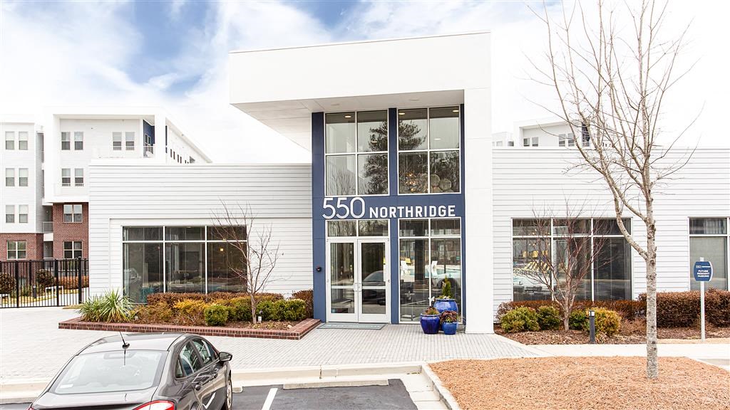 a white building with a blue sign and a car parked in front of it