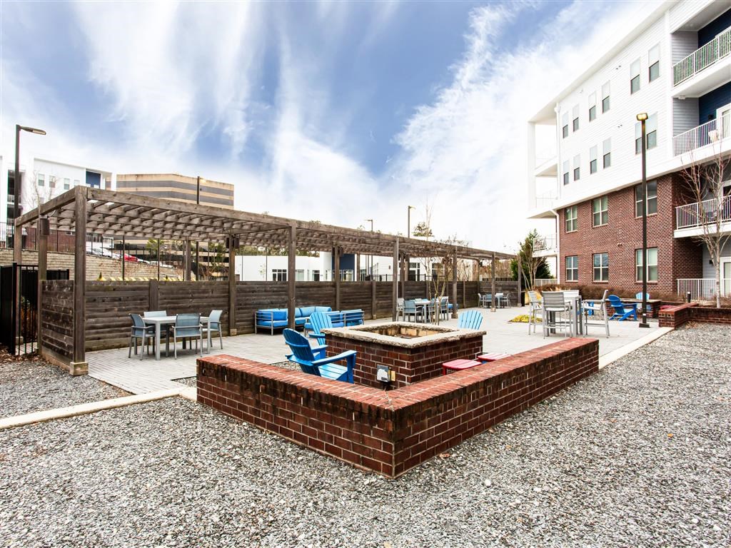 a patio with a fire pit and blue chairs
