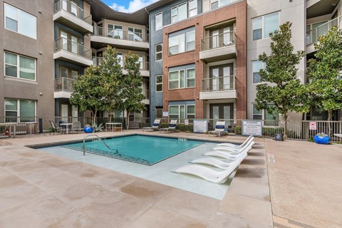 A large swimming pool in the middle of a courtyard surrounded by apartment buildings.