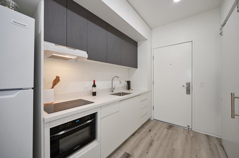 a kitchen with white cabinets and a refrigerator and a sink