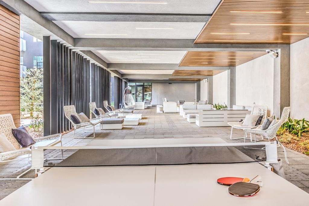 a lounge area with white lounge chairs and a ping pong table