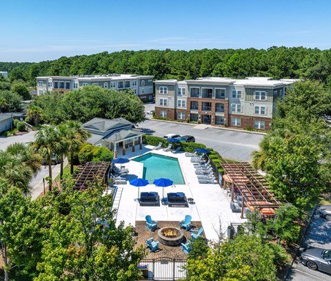 An aerial view of a resort with a swimming pool and palm trees.