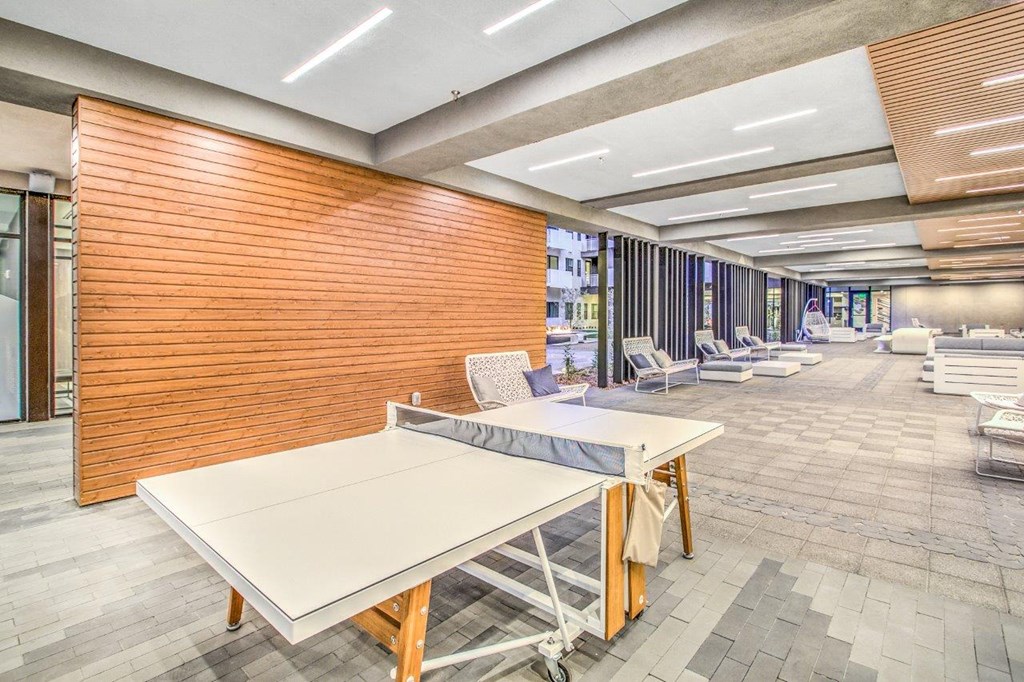 a large room with a ping pong table and lounge chairs