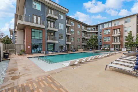 A large swimming pool in front of apartment buildings.