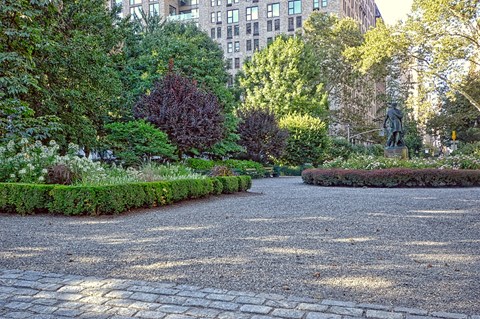 a park with trees and bushes and a statue