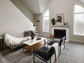 A living room with a grey couch, a coffee table, a fireplace, and a painting of a lion.