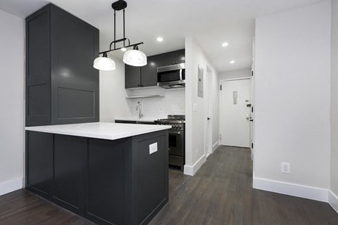a renovated kitchen with black cabinets and a white counter top in a new home