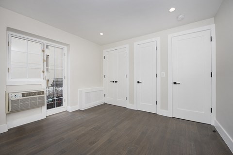 a bedroom with hardwood floors and white walls