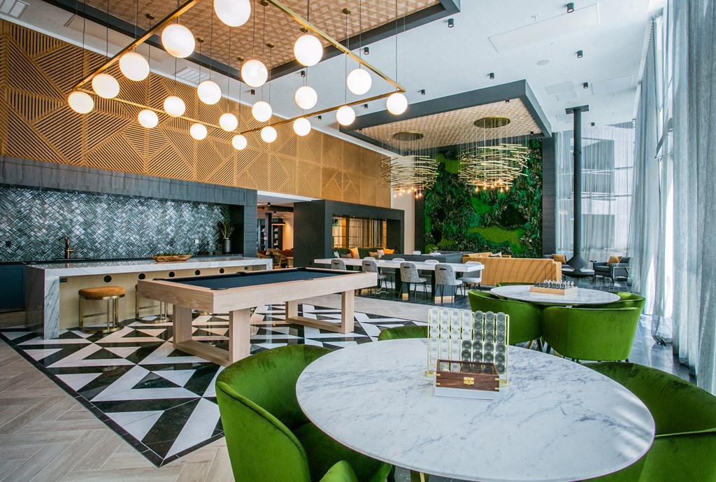 Clubhouse Lounge sitting area with yellow couches green accent wall and tables with green chairs