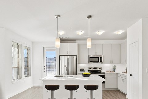 a kitchen with white cabinets and a white island with three stools