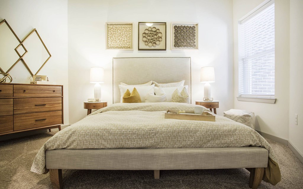 A bedroom with a large bed, a wooden dresser, and a mirror.