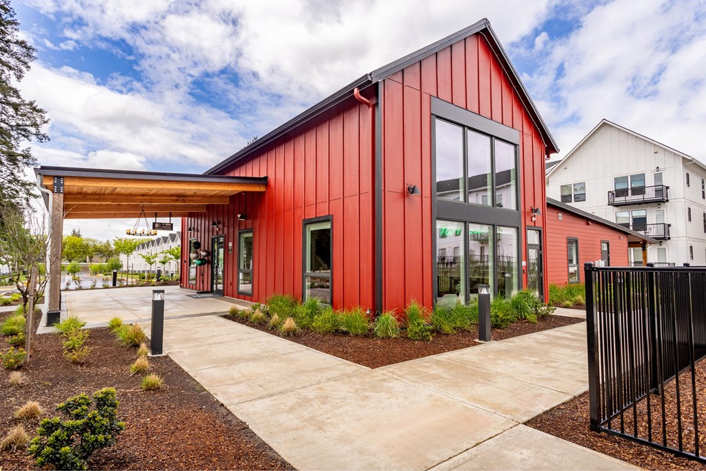 the facade of a red building with glass windows and a sidewalk at The Farmstead, Vancouver, 98684