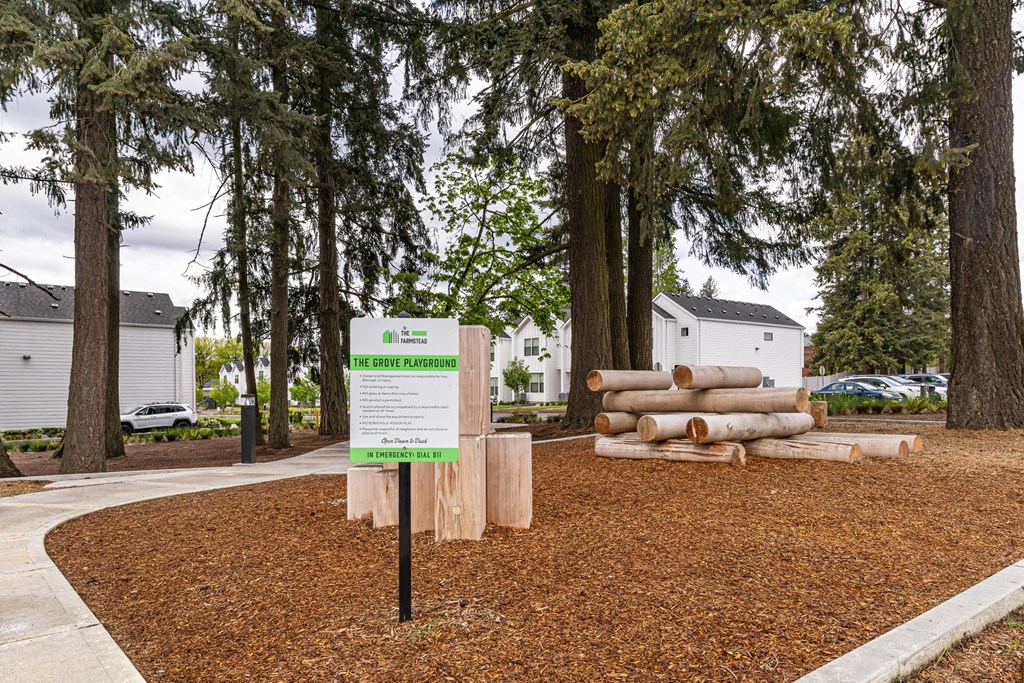 a sign and logs in a yard in front of trees at The Farmstead, Washington, 98684