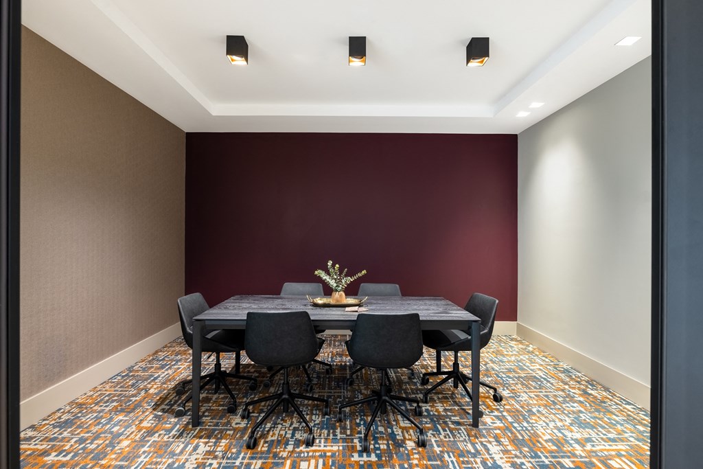a conference room with a table and chairs and a red wall