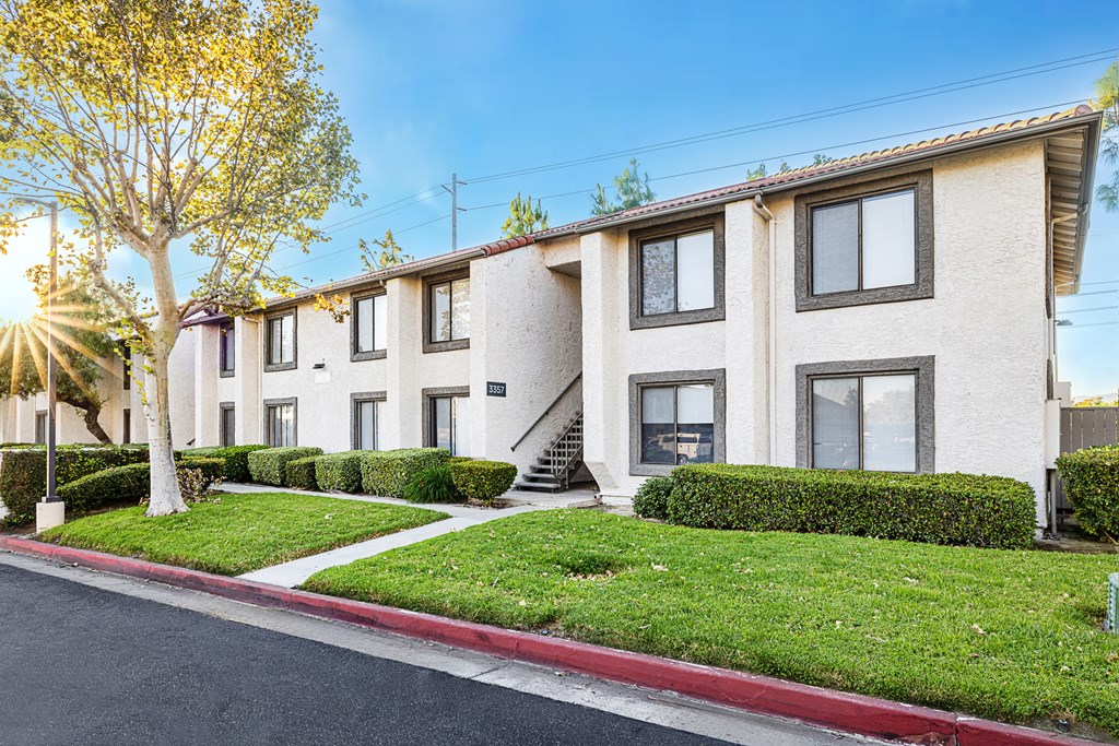 a row of apartment buildings with green grass and a sidewalk