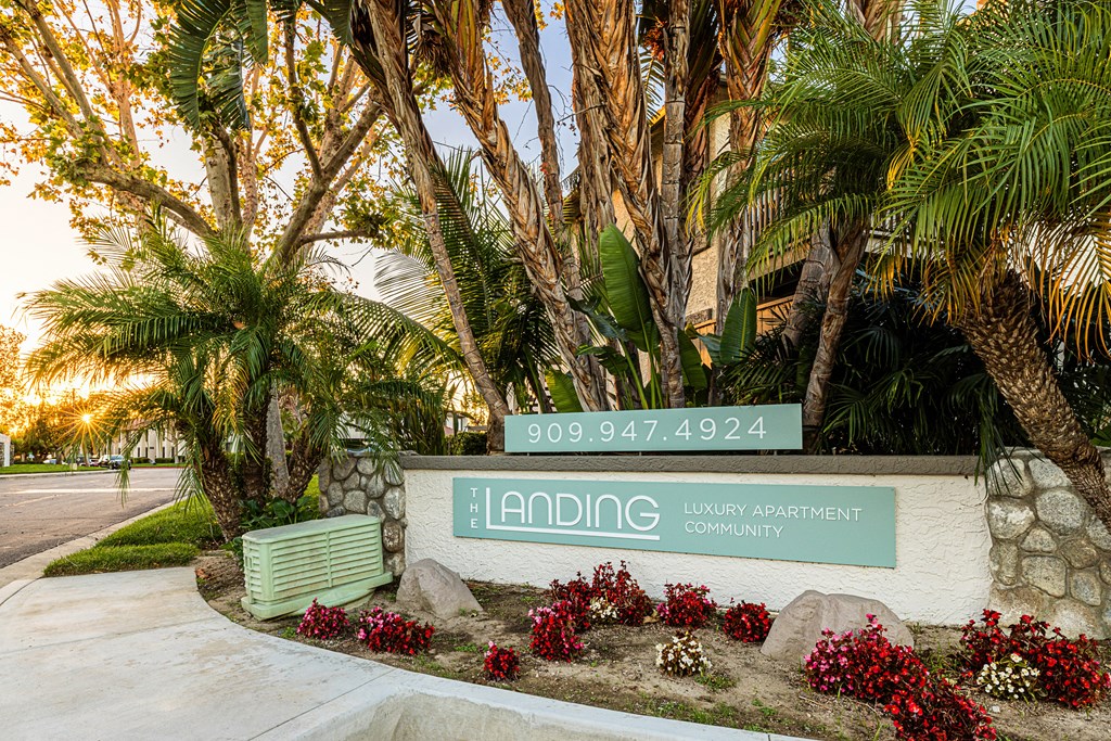 a green and white sign with palm trees and a bench