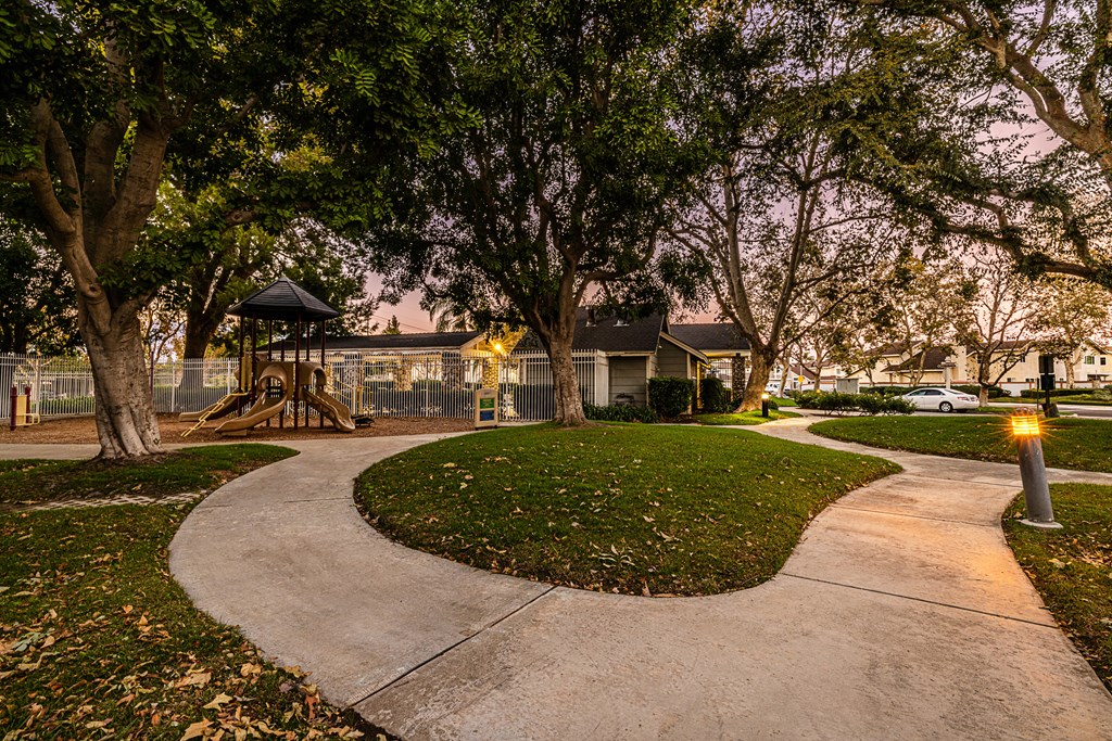 a walkway through a park with a playground and trees