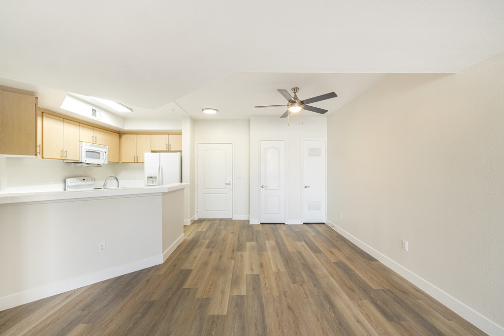 A room with a ceiling fan and wooden flooring.