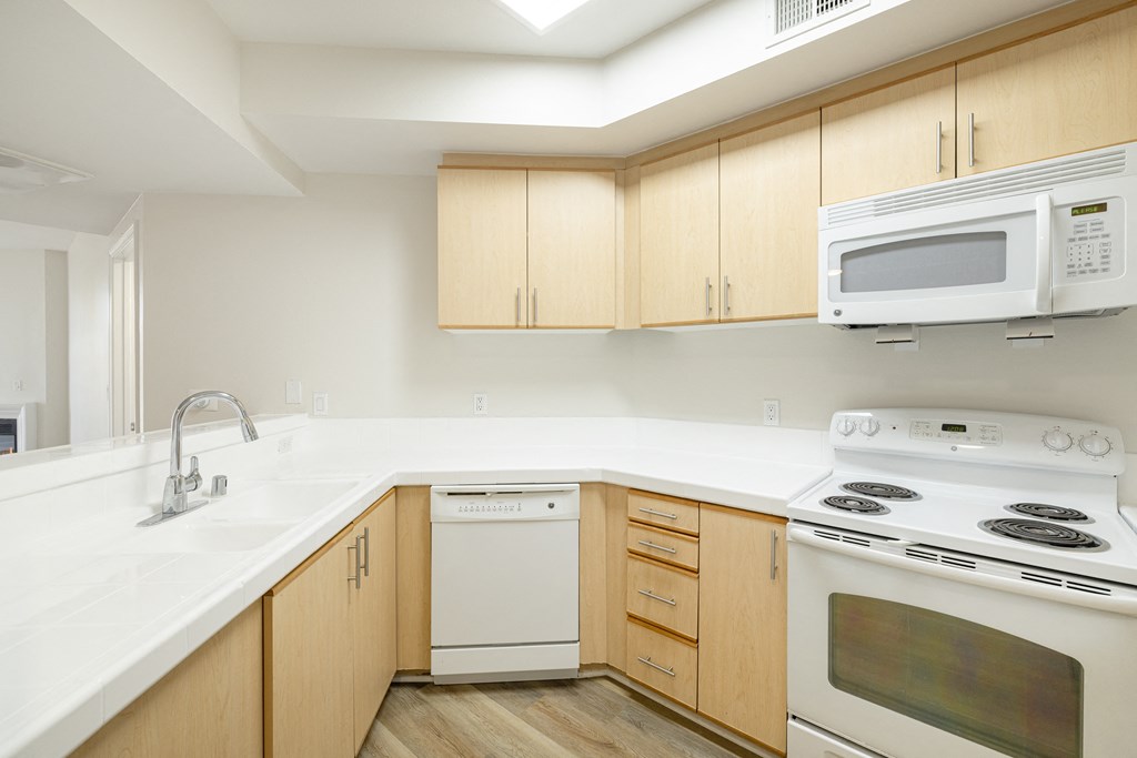 A kitchen with a white counter top and wooden cabinets.