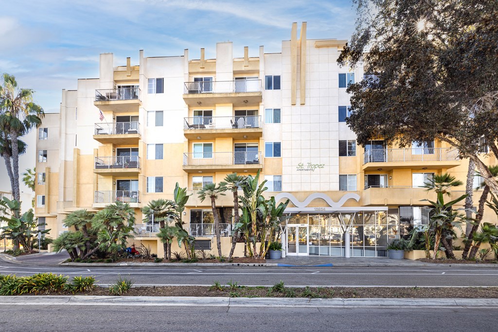 A large white building with a yellow stripe on the side and balconies on the second floor.