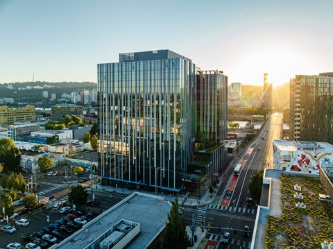A modern glass building is situated in a city with a busy road in front of it.