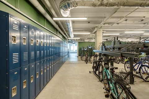 A bike rack with bicycles in a room with lockers.