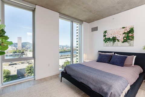 A bedroom with a large bed and a view of the city.