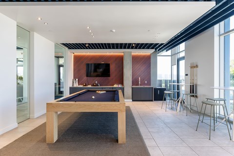 A pool table is in the middle of a room with a television and a chair.