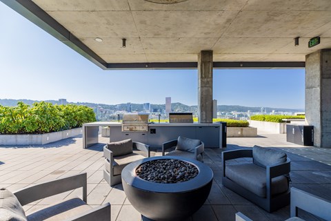 A patio with a fire pit and chairs.